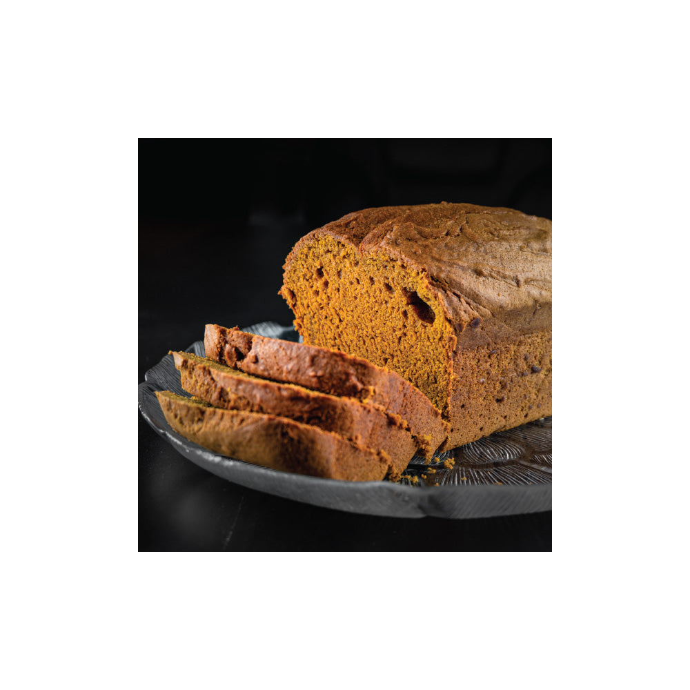 Loaf of sliced pumpkin quick bread on a dark surface