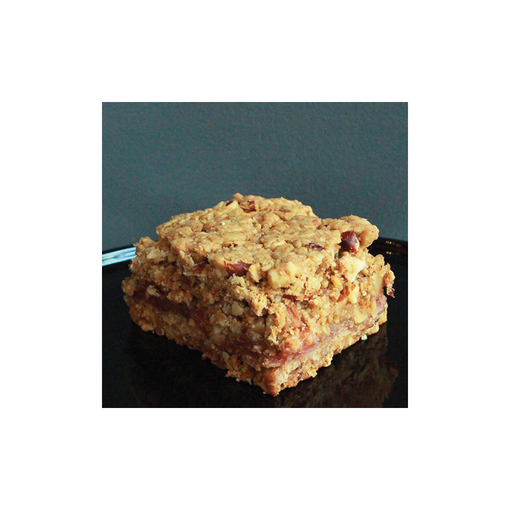 Square piece of vegan oat bar on a dark surface with a gray background